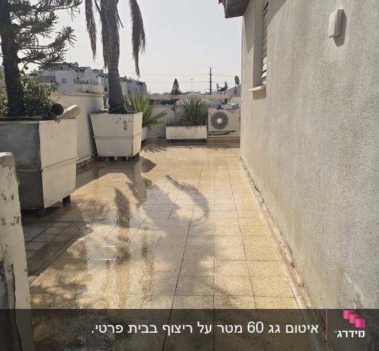 מרפסת עם רצפה רטובה וצמחייה בעציצים